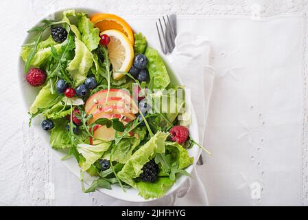 Salade verte saine avec fruits aux baies et aux pommes sur fond blanc. Salade fraîche avec fruits et légumes verts. Une alimentation saine. Banque D'Images