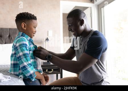 L'image d'un père afro-américain aide son fils à changer Banque D'Images