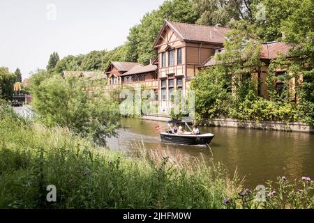 Les gens naviguant dans un petit bateau à moteur sur un canal par une journée chaude et ensoleillée à Amsterdam, pays-Bas. Banque D'Images