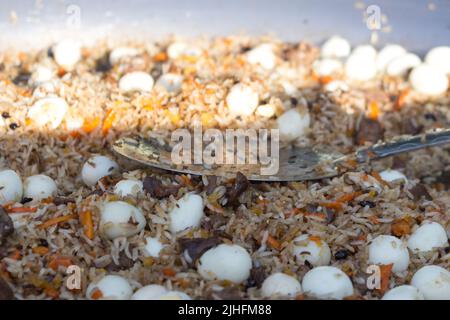 Pilaf avec des œufs de caille dans une grande poêle pendant la cuisson, gros plan Banque D'Images