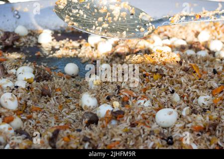 Pilaf avec des œufs de caille dans une grande poêle pendant la cuisson, gros plan Banque D'Images