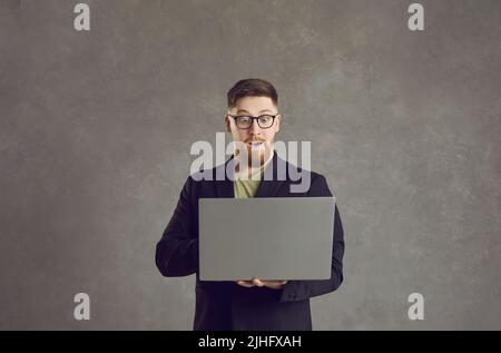Portrait d'un homme d'affaires à la barbe choqué tenant un ordinateur portable exprimant sa surprise Banque D'Images