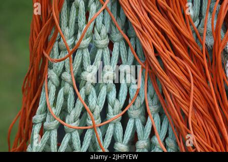 filet de poisson noué turquoise et lignes de plastique orange accrochées à l'extérieur Banque D'Images