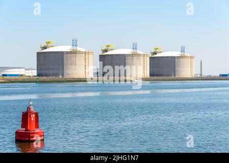 Terminal de gaz naturel liquéfié avec de grands réservoirs en béton le long d'un port par une journée ensoleillée Banque D'Images