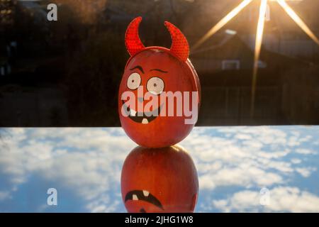 La grande citrouille orange avec un visage peint d'Halloween se dresse sur un miroir qui reflète le ciel, éclairé par le soleil couchant. Lumière et obscurité, appro Banque D'Images