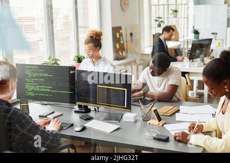 Groupe de programmeurs travaillant en équipe avec le nouveau projet à la table derrière la fenêtre au bureau Banque D'Images