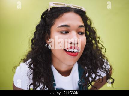 Gros plan belle femme de mode de course mixte avec des lunettes de soleil sur sa tête contre un fond de mur vert lime dans la ville. Jeune femme hispanique heureuse Banque D'Images