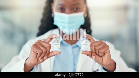 Médecin tenant des bouteilles de la cure covid. Prêt à sauver le monde du covid. Un médecin afro-américain tient des flacons du virus corona Banque D'Images