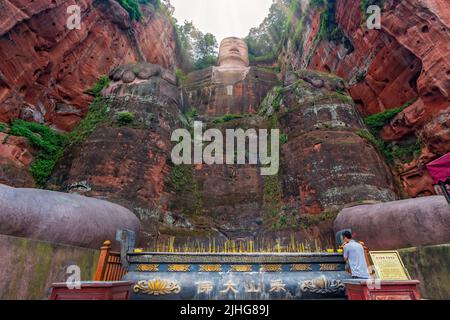 Leshan, Chine - juillet 2019 : des bougies commémoratives éclairantes d'hommes chinois en pèlerinage au fond du Bouddha géant de Leshan, une statue en pierre de 71 mètres de haut Banque D'Images