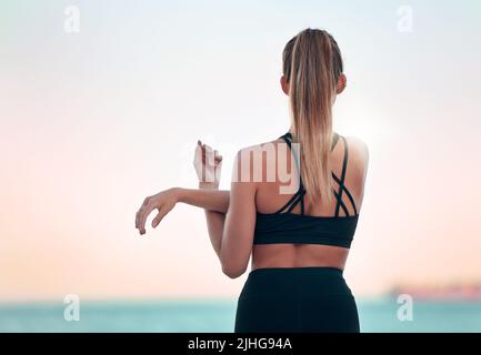 Vision belle femme pratiquant l'exercice de yoga sur la plage. Jeune athlète féminine s'étirant et se réchauffant tout en faisant de l'entraînement à l'extérieur. Recherche Banque D'Images