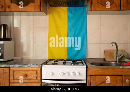 Le drapeau ukrainien est suspendu sur le mur dans la cuisine d'un appartement en Ukraine sur fond d'un poêle à gaz, la guerre en Ukraine, sans gaz Banque D'Images