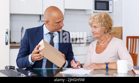 La femme et l'agent matures remplissent les documents Banque D'Images