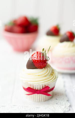 Petits gâteaux décorés de crème fouettée et de fraises enrobées de chocolat Banque D'Images