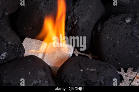 Allumer un feu de barbecue. Briquette et briquette blanche. Flamme au charbon de bois. Banque D'Images