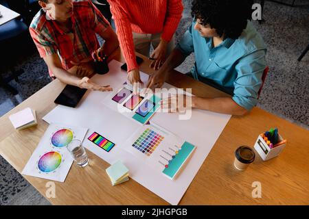 Des collègues masculins et féminins créatifs et multiraciaux discutent au-dessus des charts au bureau Banque D'Images
