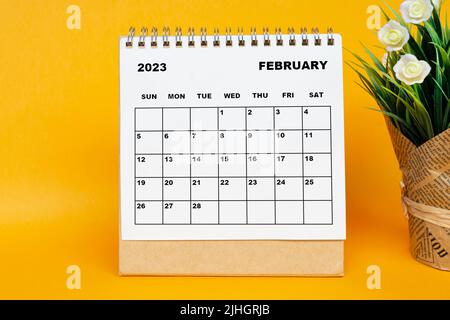 Calendrier blanc de février 2023 avec plante en pot sur fond jaune. Banque D'Images