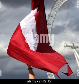 Londres, Royaume-Uni - 23 août 2020 : drapeau letton avec London Eye et ciel nuageux en arrière-plan Banque D'Images