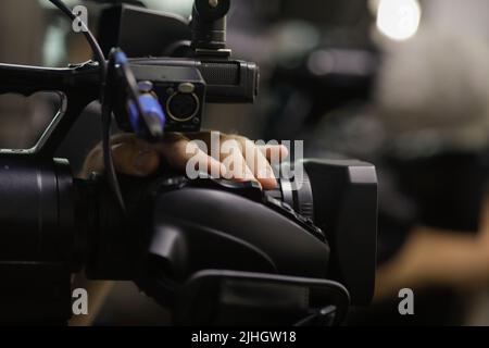 Détails de faible profondeur de champ (mise au point sélective) avec les mains d'un opérateur de caméra d'information utilisant les boutons de sa caméra pendant un événement de presse. Banque D'Images