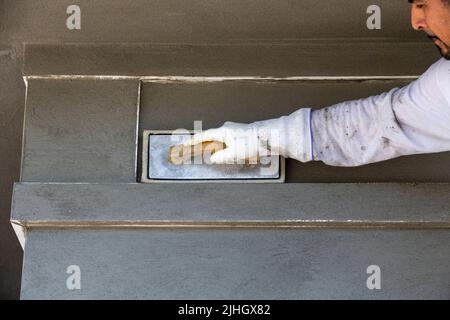 Travailleur de la construction qualifié utilisant une éponge humide pour nettoyer tout stuc des bords de la bordure du bec de coin et pour lisser le stuc Banque D'Images