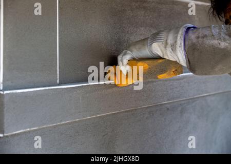 Travailleur de la construction qualifié utilisant une éponge humide pour nettoyer tout stuc des bords de la bordure du bec de coin et pour lisser le stuc Banque D'Images