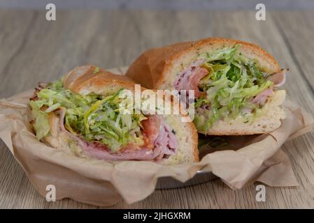 Sandwich au jambon chargé avec du fromage provolone, de la tomate, du mayonnaise et de l'oignon rouge à l'intérieur d'un rouleau italien pour un déjeuner copieux. Banque D'Images