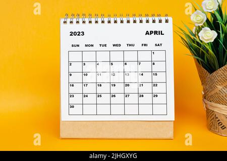 Calendrier blanc d'avril 2023 avec plante en pot sur fond jaune. Banque D'Images