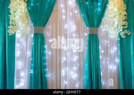 Décoration de la salle de banquet avec tissus blancs et turquoise illuminés de guirlandes. Banque D'Images