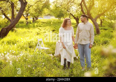 Beau jeune couple dans un endroit romantique, verger de pomme en fleur de printemps. Heureux couple joyeux profiter l'un de l'autre en marchant dans le jardin. Homme holdi Banque D'Images