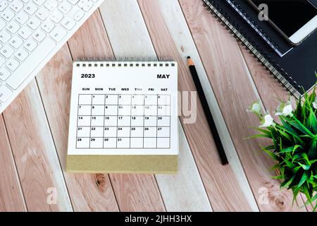 Calendrier blanc de mai 2023 sur bureau en bois avec papeterie de bureau. Banque D'Images