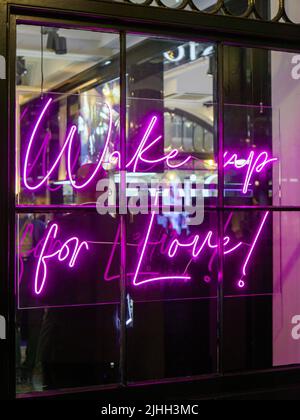 Affiche au néon « Wake up for Love » dans une fenêtre de magasin. Intérieur d'un magasin au hasard sur le fond Banque D'Images