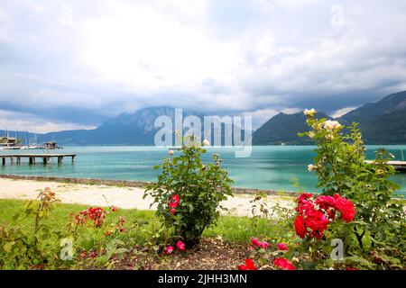 Attersee - célèbre lac turquoise autrichien. La vue sur les rosiers, la jetée et les montagnes en arrière-plan. Ciel nuageux. Banque D'Images