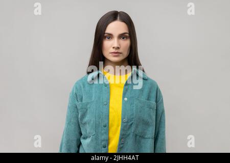 Portrait d'une femme robuste qui regarde l'appareil photo, se sent confiante et sûre d'elle-même, exprimant son sérieux, portant une veste de style décontracté. Prise de vue en studio isolée sur fond gris. Banque D'Images