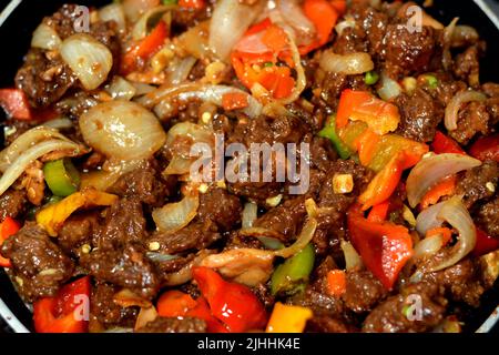 Cuisine chinoise de bœuf grillé morceaux de viande rouge et cubes avec huile, champignons, légumes, petits pois, carottes, poivrons colorés, cloche, piment, on Banque D'Images