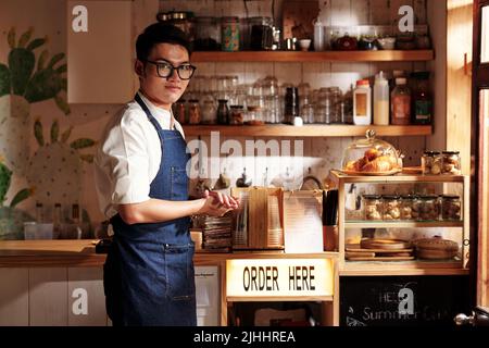 Portrait d'un jeune homme vietnamien souriant qui fait des affaires de coffeeshop Banque D'Images