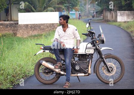 Un jeune indien qui fait une moto près d'un champ de paddy Banque D'Images