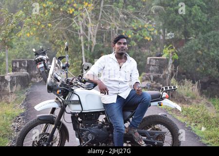 Un jeune indien qui fait une moto près d'un champ de paddy Banque D'Images