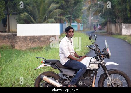 Un jeune indien qui fait une moto près d'un champ de paddy Banque D'Images