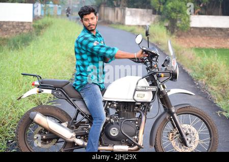 Un jeune indien qui fait une moto près d'un champ de paddy Banque D'Images