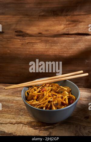 Bami Goreng, spécialité indonésienne de pâtes dans un bol en bois avec baguettes Banque D'Images