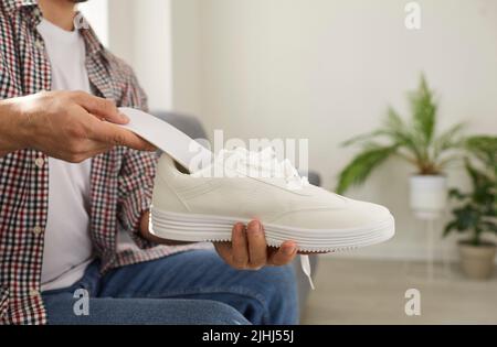 L'homme met une nouvelle semelle intérieure orthèse avec soutien de la voûte plantaire à l'intérieur d'une chaussure orthopédique confortable Banque D'Images