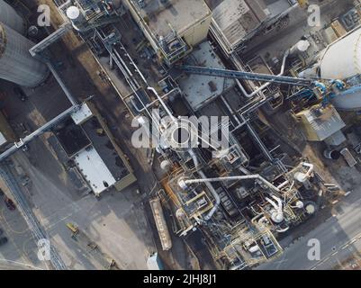 Une vue aérienne de près directement au-dessus d'une cheminée industrielle ou d'une cheminée dans une grande usine de fabrication pendant une journée. Banque D'Images