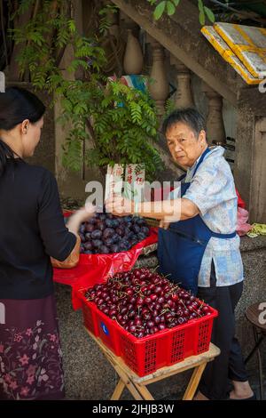 Un vendeur de rue vend des cerises et des prunes, dans le centre de l'île de Hong Kong Banque D'Images