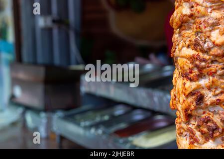 Gros plan de torréfaction de viande empilée à utiliser dans la préparation de gyros traditionnels grecs ou de doner turc. Espace de copie avec arrière-plan flou Banque D'Images