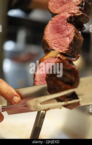 Picanha est un barbecue viande grillée au charbon de bois. Couteau coupant sur brochette. Viande brésilienne dans un restaurant Churrascaria Banque D'Images