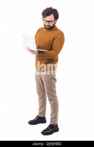 Homme élégant et bien entretenu avec l'ordinateur portable debout et dactylographiant - isolé sur fond blanc. Photo de haute qualité Banque D'Images