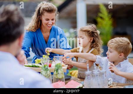 Famille ayant la fête du jardin, les enfants mangent des collations, rient et s'amusent. Banque D'Images