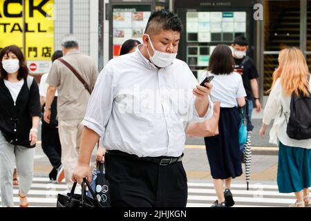 Tokyo, Japon. 19th juillet 2022. Des personnes portant des masques protecteurs pour aider à freiner la propagation du coronavirus marchent dans le centre-ville de Tokyo. Tokyo a confirmé mardi 11 018 cas de COVID-19 pour la huitième journée consécutive. (Image de crédit: © Rodrigo Reyes Marin/ZUMA Press Wire) Banque D'Images