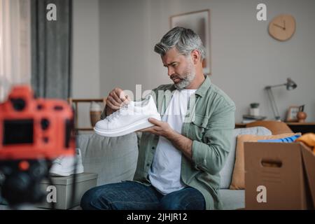 Un grand blogueur européen de style ancien avec des enregistrements de barbe vidéo sur les chaussures, regardez les baskets Banque D'Images