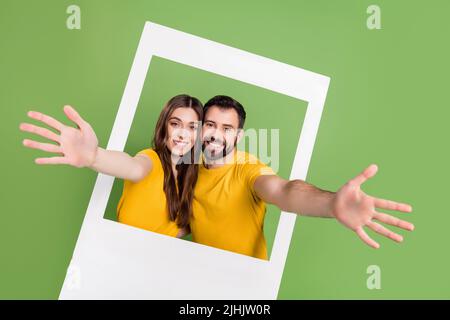 Portrait de positif beau gars jolie dame lever les mains inviter par carte d'album isolé sur fond vert couleur Banque D'Images