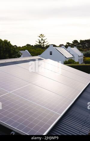 Panneaux solaires sur les toits des maisons et des arbres poussant contre le ciel nuageux au coucher du soleil, espace de copie Banque D'Images